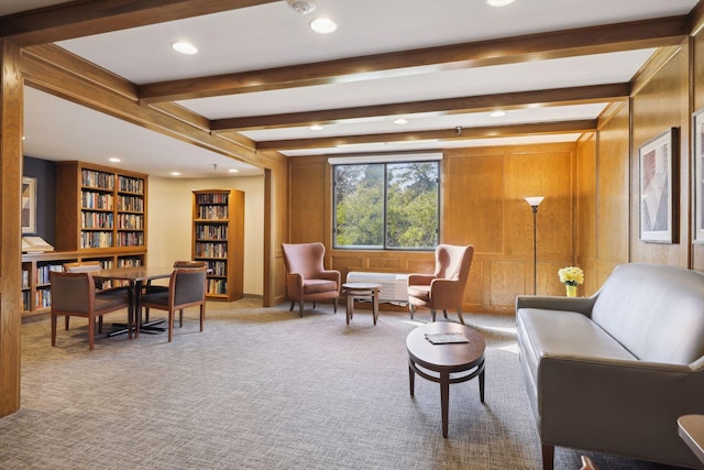 sitting room with wooden walls, beamed ceiling, and carpet floors