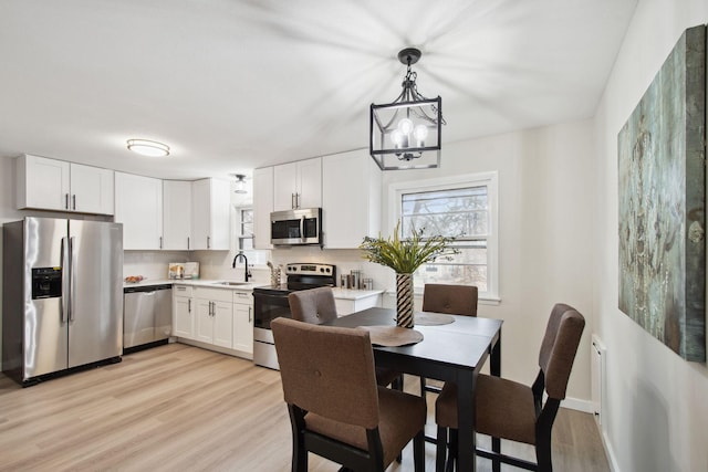 dining room featuring light hardwood / wood-style floors, sink, and an inviting chandelier