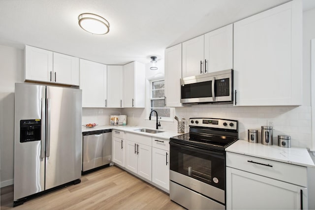 kitchen with white cabinetry, sink, tasteful backsplash, light hardwood / wood-style flooring, and appliances with stainless steel finishes