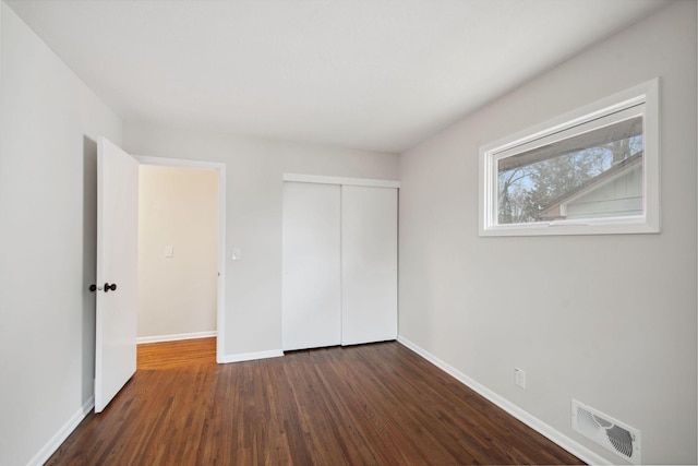 unfurnished bedroom with dark hardwood / wood-style flooring and a closet