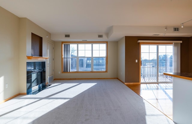 unfurnished living room featuring a tile fireplace and light colored carpet