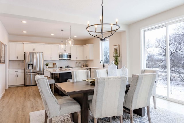 dining area featuring sink, a notable chandelier, and light hardwood / wood-style flooring