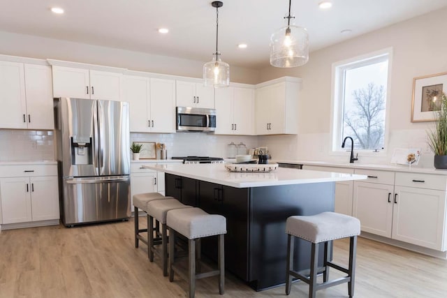 kitchen with a breakfast bar, white cabinetry, hanging light fixtures, stainless steel appliances, and a center island