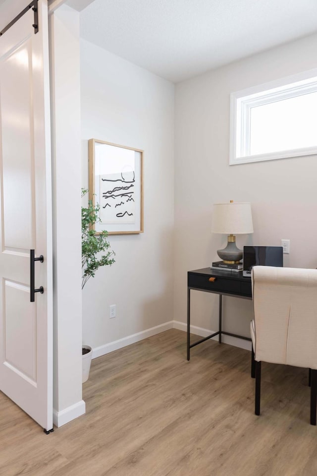 office area featuring a barn door and light hardwood / wood-style floors