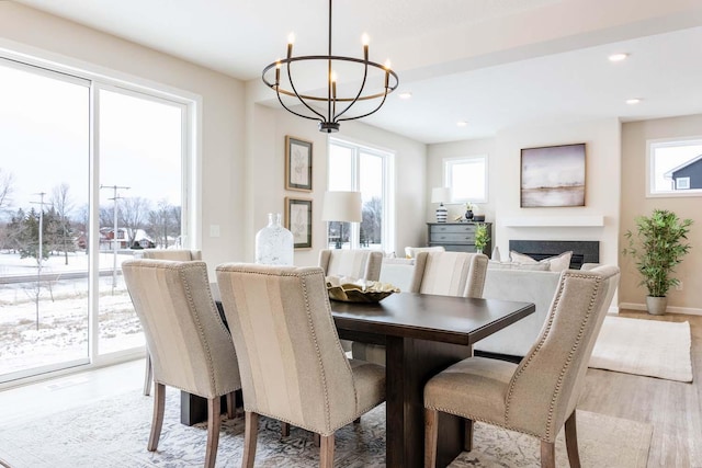 dining room with an inviting chandelier, a wealth of natural light, and light wood-type flooring