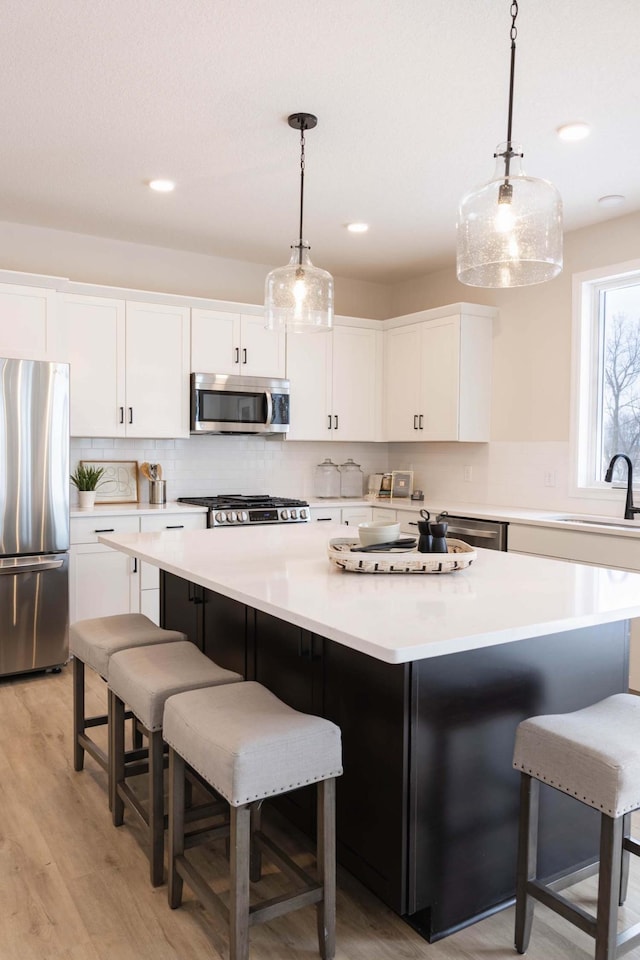 kitchen with stainless steel appliances, a center island, sink, and white cabinets