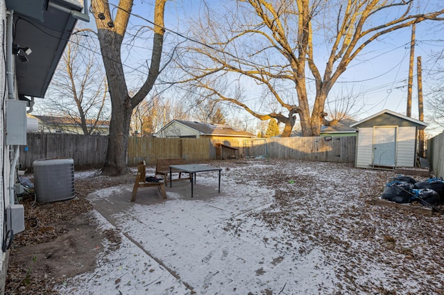 yard covered in snow with central AC and a storage shed