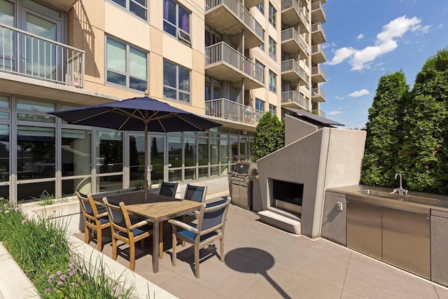 view of patio with grilling area, sink, an outdoor kitchen, and an outdoor fireplace