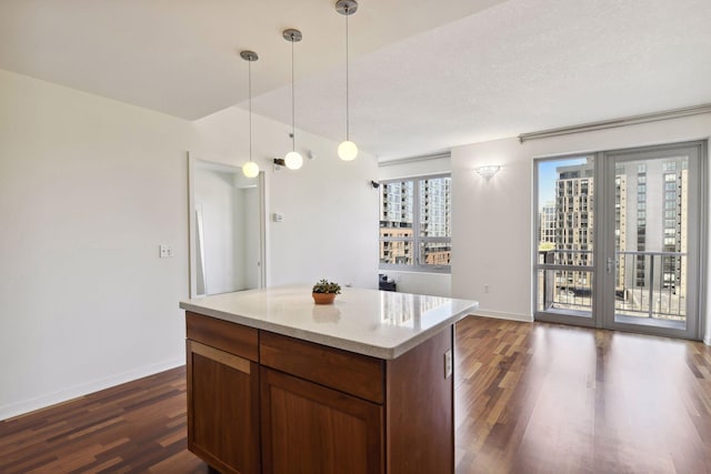 kitchen featuring dark hardwood / wood-style flooring, a center island, hanging light fixtures, and a textured ceiling