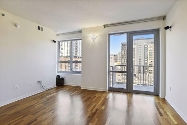 spare room featuring a textured ceiling and dark hardwood / wood-style floors