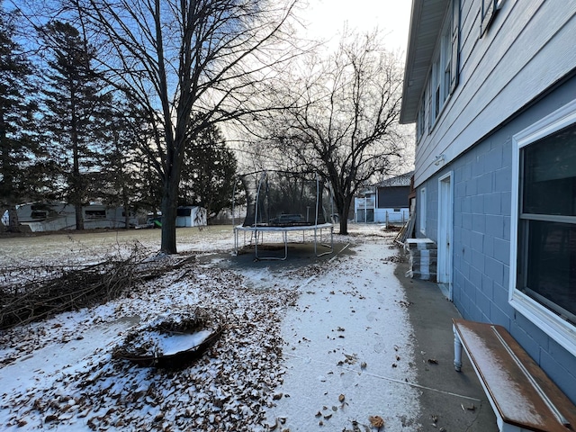 yard covered in snow with a trampoline and a storage shed