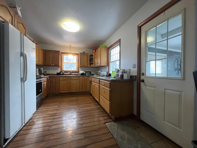 kitchen featuring sink, dark wood-type flooring, hanging light fixtures, white fridge, and stainless steel electric range