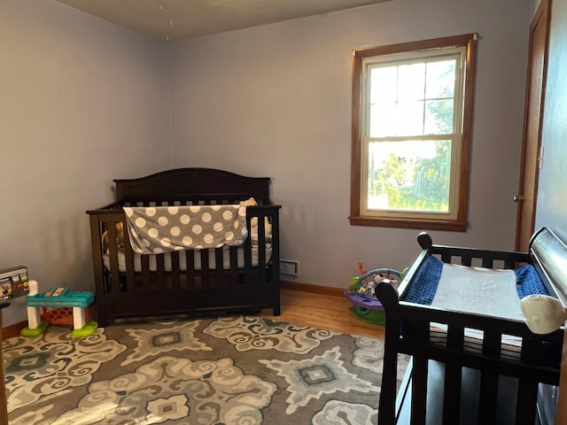 bedroom with hardwood / wood-style floors and a nursery area