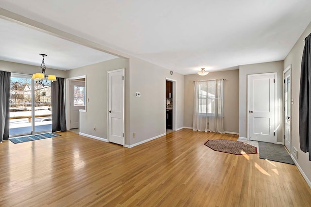 foyer with a notable chandelier, plenty of natural light, and light hardwood / wood-style floors