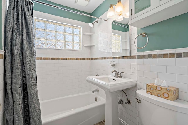 bathroom featuring shower / bath combo, tile walls, and toilet