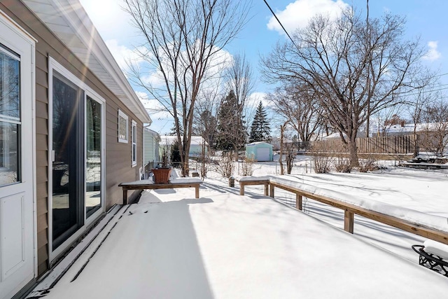 snow covered patio featuring a storage shed