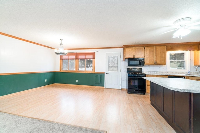 kitchen featuring black appliances, decorative light fixtures, light wood-type flooring, and a wealth of natural light