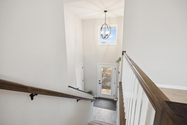 stairs with a notable chandelier, plenty of natural light, baseboards, and wood finished floors