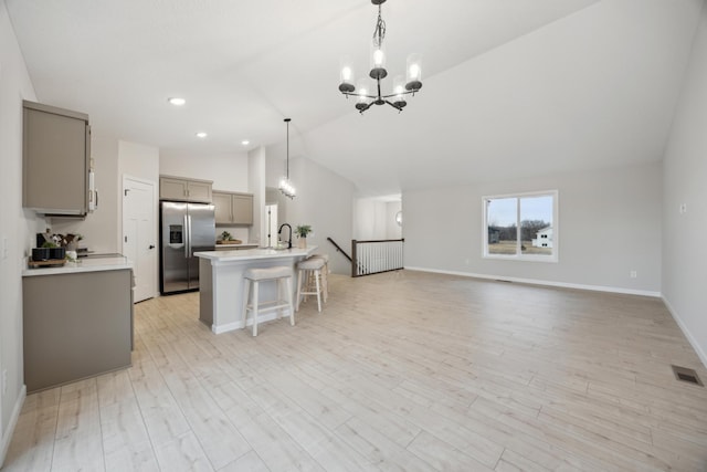 kitchen with a chandelier, a breakfast bar, visible vents, gray cabinets, and stainless steel fridge with ice dispenser