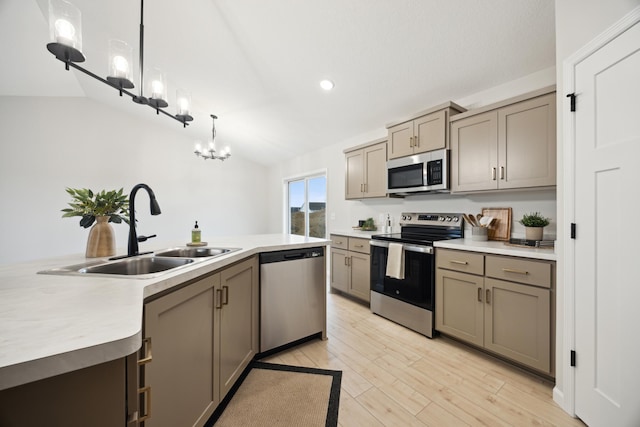 kitchen with an inviting chandelier, appliances with stainless steel finishes, vaulted ceiling, a sink, and light wood-type flooring