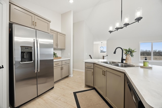 kitchen featuring appliances with stainless steel finishes, light countertops, a sink, and gray cabinetry