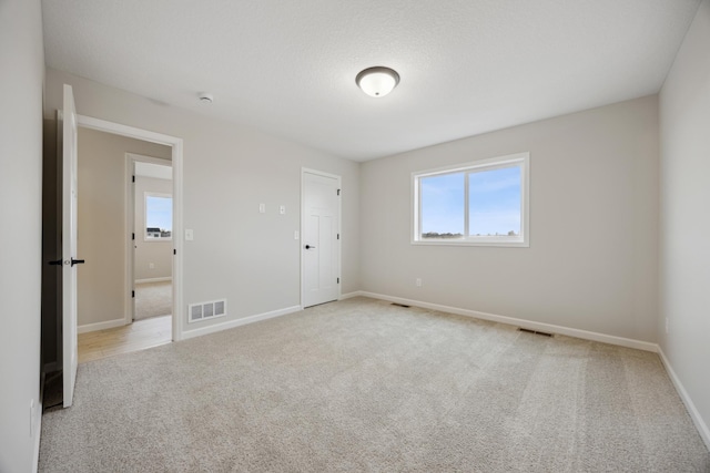 unfurnished room featuring carpet floors, visible vents, and baseboards