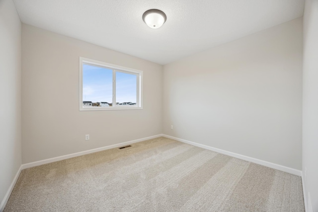 unfurnished room with carpet floors, visible vents, baseboards, and a textured ceiling