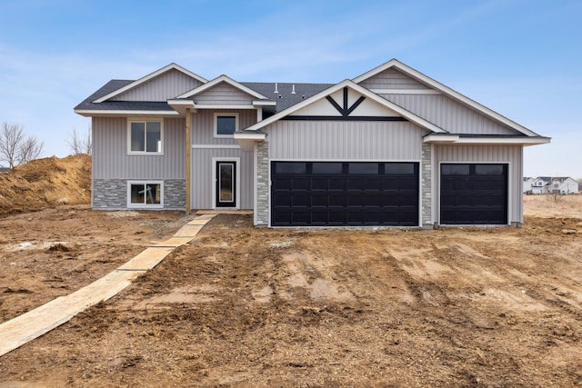 view of front of house with driveway, stone siding, an attached garage, and a shingled roof