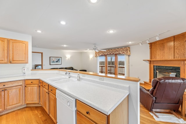 kitchen with a fireplace, sink, white dishwasher, and light hardwood / wood-style floors