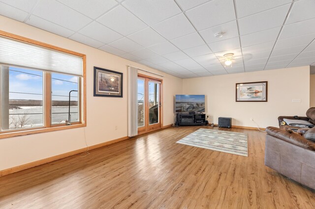 living room with light hardwood / wood-style flooring and a drop ceiling