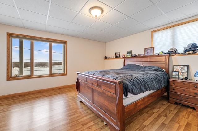 bedroom with light wood-type flooring and a paneled ceiling