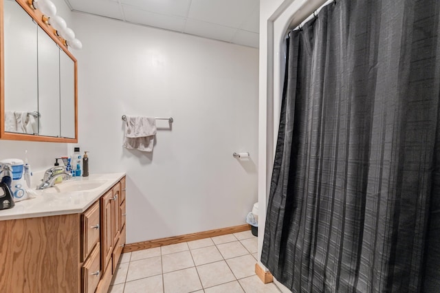 bathroom with tile patterned flooring, a drop ceiling, and vanity