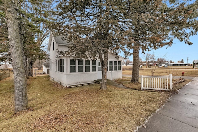 view of side of home featuring a lawn and a sunroom