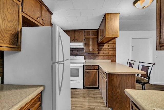 kitchen with a breakfast bar, white appliances, hardwood / wood-style flooring, and tasteful backsplash