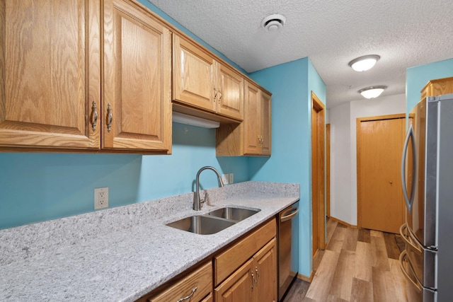 kitchen with light hardwood / wood-style flooring, stainless steel appliances, a textured ceiling, and sink