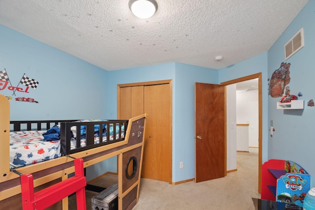 bedroom featuring light colored carpet, a textured ceiling, and a closet