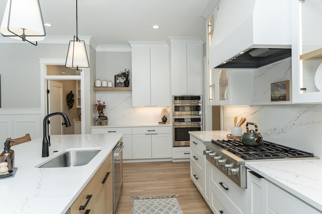 kitchen with crown molding, open shelves, custom range hood, appliances with stainless steel finishes, and a sink