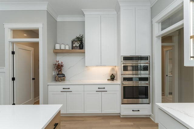 kitchen with double oven, white cabinetry, decorative backsplash, open shelves, and crown molding