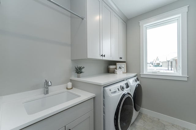 laundry room with baseboards, a sink, cabinet space, and washer and dryer