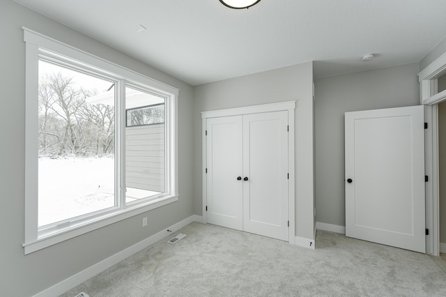 unfurnished bedroom with carpet floors, a closet, visible vents, and baseboards