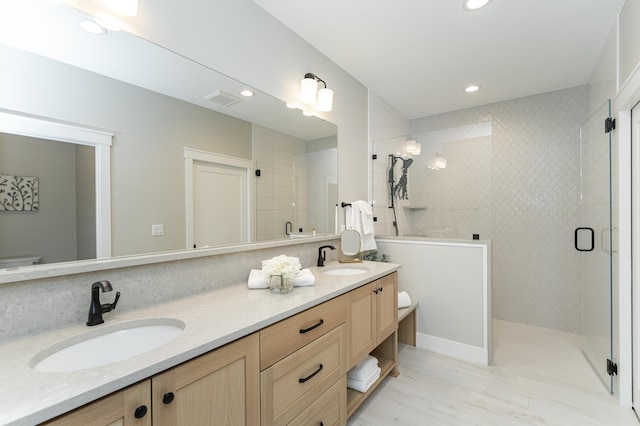 bathroom featuring double vanity, a stall shower, and a sink