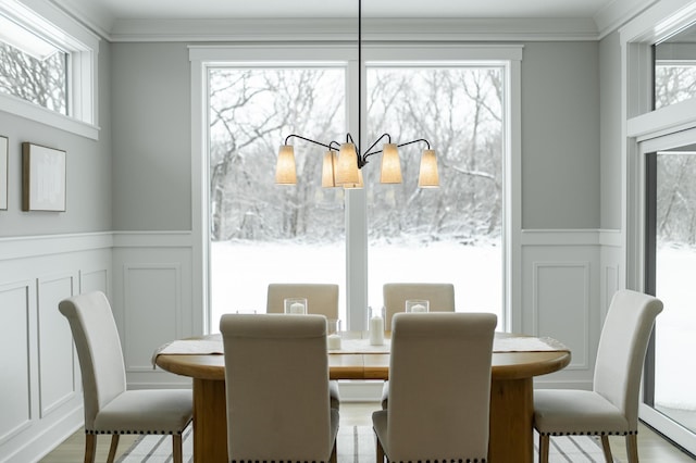 dining area with a wainscoted wall, ornamental molding, wood finished floors, and a decorative wall