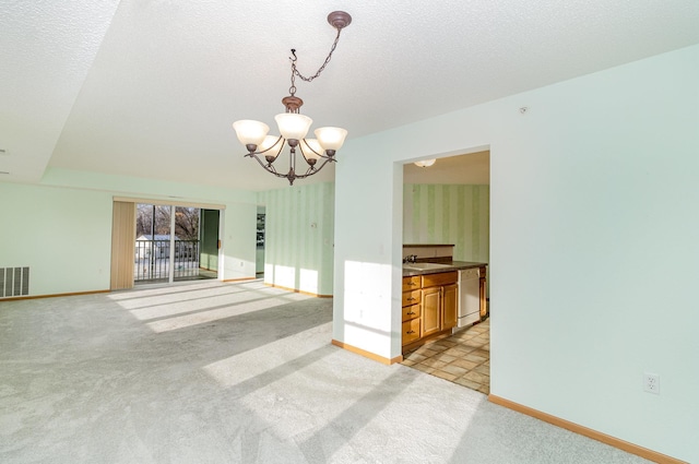 unfurnished room featuring light colored carpet, sink, a textured ceiling, and a notable chandelier