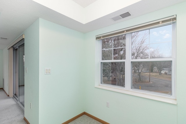 carpeted empty room featuring a textured ceiling