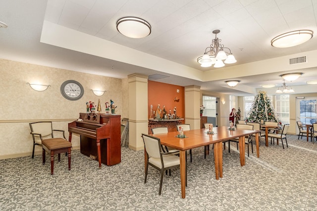 dining space featuring an inviting chandelier, a raised ceiling, and carpet