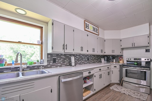 kitchen with backsplash, sink, light wood-type flooring, and appliances with stainless steel finishes