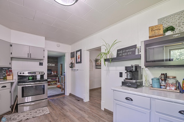 kitchen featuring crown molding, appliances with stainless steel finishes, and light hardwood / wood-style flooring