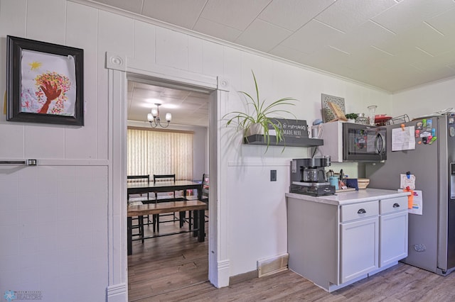 kitchen with a chandelier, hardwood / wood-style floors, stainless steel appliances, and ornamental molding