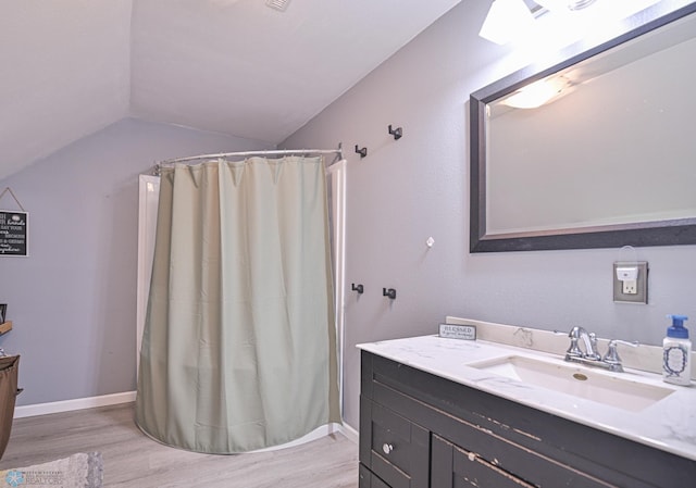 bathroom with hardwood / wood-style floors, vanity, lofted ceiling, and walk in shower