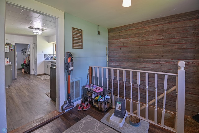 hallway with dark hardwood / wood-style flooring and wooden walls